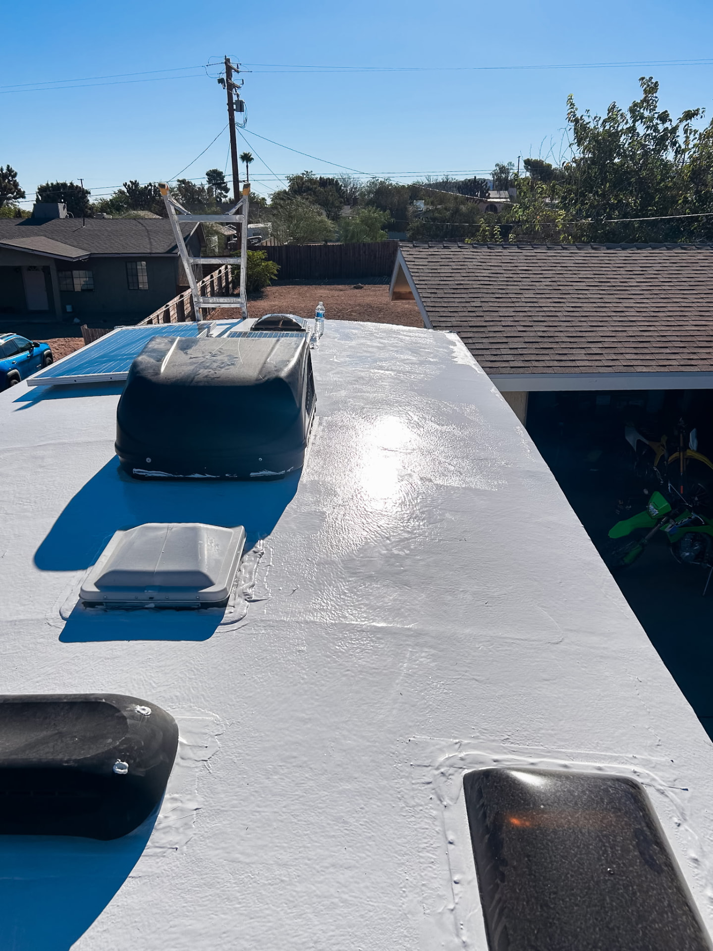 Freshly coated white RV roof with vents and an air conditioner in the sun