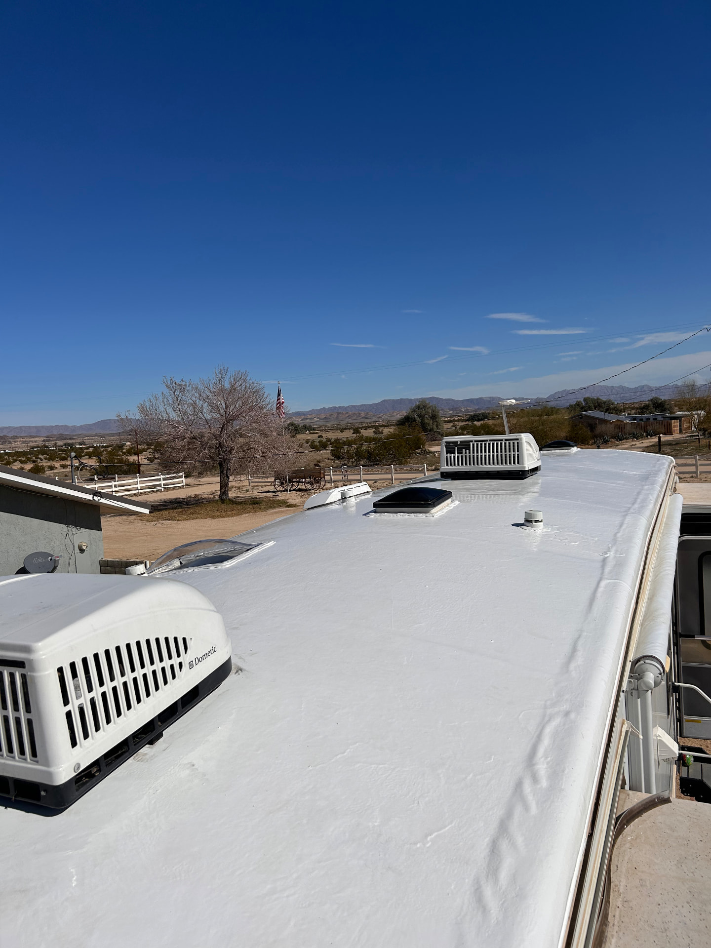 Freshly coated RV roof with air conditioning units at a desert service visit