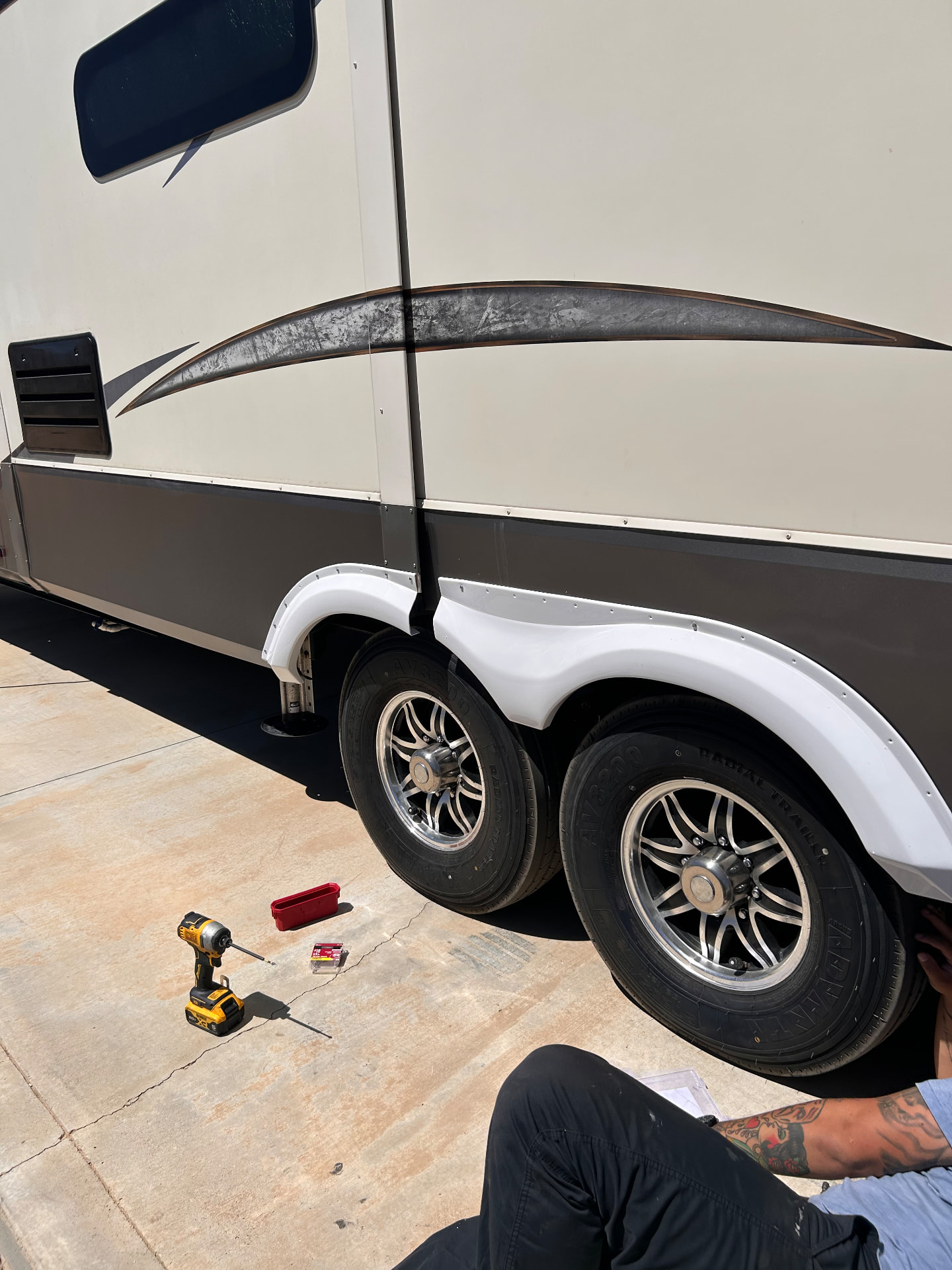 Technician working beside the wheels of a fifth wheel
