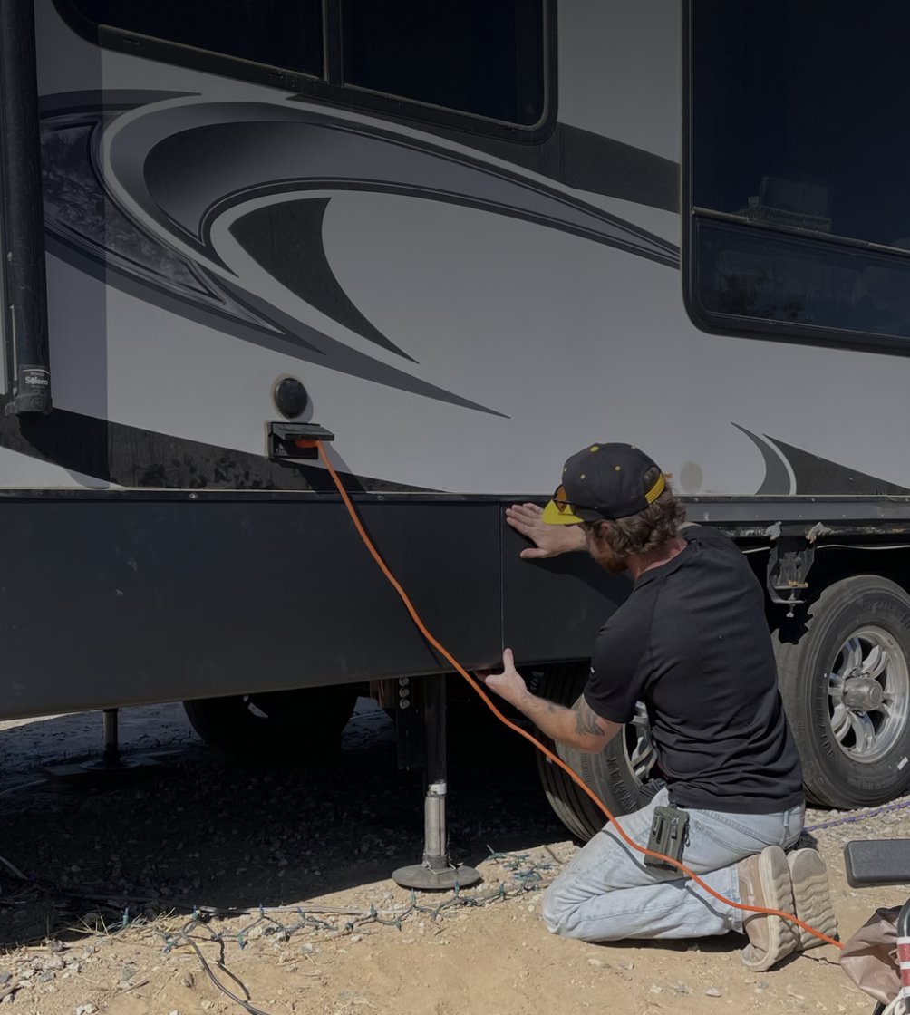 Technician installing metal skirting on the underbelly of an RV